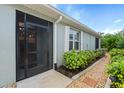 Exterior view featuring a screened-in entry, well-kept garden bed and pathway at 7497 W Lenox Cir, Punta Gorda, FL 33950