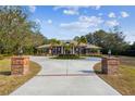 Beautiful home exterior featuring a circular driveway, brick pillars, and mature trees against a blue sky at 9606 Braden Run, Bradenton, FL 34202
