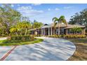 Charming brick home with a circular driveway, lush landscaping, and a welcoming columned entrance at 9606 Braden Run, Bradenton, FL 34202