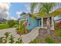 Beautiful home with blue siding, a charming front porch, and tropical landscaping at 11008 Sand Pine Ln, Parrish, FL 34219
