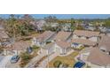 Aerial view showing a collection of townhomes with a mix of beige exteriors, brown roofs, and tree landscaping at 11743 Rolling Pine Ln, Port Richey, FL 34668