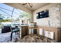 This outdoor kitchen features a built-in grill, refrigerator, sink, and TV for outdoor entertainment at 13452 Canopy Creek Dr, Tampa, FL 33625