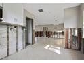 Open concept space with a kitchen featuring white cabinets and a large living area with a light-colored tile floor at 2491 Coronado Way, Dunedin, FL 34698