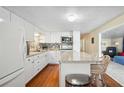 Modern kitchen with white cabinetry, a sleek island with barstools, and hardwood flooring at 37150 Sandra Ave, Zephyrhills, FL 33542