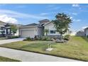 Front exterior of a cozy home featuring a lush lawn, stone accents, and a convenient two-car garage at 5125 Tannin Ln, Bradenton, FL 34211