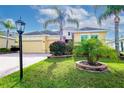 Inviting exterior with a brick driveway, lush green lawn, mature palm trees, and colorful floral landscaping at 1605 Emerald Dunes Dr, Sun City Center, FL 33573