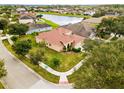 Aerial view of a beige two-story home with a tile roof, three-car garage, and nearby pond at 2604 Dakota Rock Dr, Ruskin, FL 33570