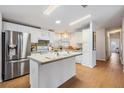 Well-lit kitchen with stainless steel refrigerator, center island, and white cabinetry at 36645 Kay Ave, Zephyrhills, FL 33542