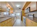 Galley kitchen featuring tile flooring, stainless steel appliances, and light wood cabinetry at 5313 Baroque Dr, Holiday, FL 34690