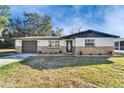 A well-maintained home features a stone facade, a well-kept lawn, and an attached garage at 5602 Bay Blvd, Port Richey, FL 34668