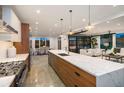 Open kitchen featuring a large island with a marble countertop and modern pendant lighting at 561 173Rd E Ave, North Redington Beach, FL 33708