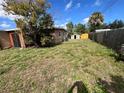 Wide view of back yard featuring shed and wood fence, with scattered foliage at 7563 Meadowlawn N Dr, St Petersburg, FL 33702