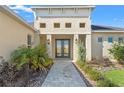Close-up of the front entrance with double doors, stone walkway, and well-maintained landscaping at 8977 Players Dr, Brooksville, FL 34613
