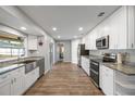 Modern kitchen with stainless steel appliances, granite countertops, white cabinets, and durable wood-look flooring at 1240 Ridgegrove S Dr, Palm Harbor, FL 34683