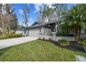 Well-maintained single-story home with a two-car garage, palm tree, and landscaped yard at 887 Lucas Ln, Oldsmar, FL 34677
