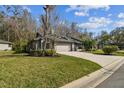 Well-maintained single-story home with green lawn, and mature trees on a sunny day at 887 Lucas Ln, Oldsmar, FL 34677