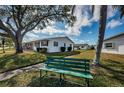 Scenic view of a single-story home with a manicured lawn, lush trees, and a park bench in a serene neighborhood at 10022 Lily N St # N, Pinellas Park, FL 33782