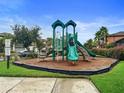 Community playground featuring slides, climbing structures, and a safety surface, surrounded by lush landscaping at 11008 Tahiti Isle Ln, Tampa, FL 33647