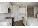 Well-lit kitchen showcasing white cabinets, stainless steel appliances, and a functional layout with wood-look floors at 14441 Meadow Bird Ave, Riverview, FL 33579