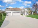Well-maintained single-story home featuring a three-car garage, arched entry and green lawn at 1545 Deerbourne Dr, Wesley Chapel, FL 33543