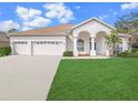 Well-maintained single-story home featuring a three-car garage, arched entry and green lawn at 1545 Deerbourne Dr, Wesley Chapel, FL 33543