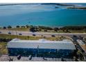 Stunning aerial view of the building featuring the waterfront location, lush trees, and highway at 2 Causeway Blvd # 208, Dunedin, FL 34698
