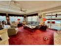 Cozy living room featuring plush red carpet, ample seating, and an abundance of natural light at 205 Seagull N Dr, Tarpon Springs, FL 34689