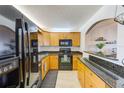 Well-lit kitchen with oak cabinets, black appliances, and granite countertops, perfect for any home chef at 7420 Bay Island S Dr # 281, South Pasadena, FL 33707