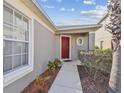Home's front door is red and accentuated with surrounding landscaping. A gray wall is visible at 8133 Canterbury Lake Blvd, Tampa, FL 33619