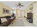 Light-filled living room featuring a brown leather sofa, a ceiling fan, and light yellow walls at 8133 Canterbury Lake Blvd, Tampa, FL 33619
