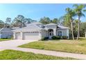 Inviting single-story home featuring a well-kept lawn, mature palm trees, and a three-car garage at 12545 Leatherleaf Dr, Tampa, FL 33626