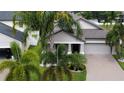 Inviting single-Gathering home with two-car garage, brick paved driveway, and mature palm trees enhancing the curb appeal at 13359 Orca Sound Dr, Riverview, FL 33579