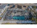 Aerial view of the screened-in pool with lounge area in a fenced backyard with solar panels at 1401 Wickham Ln, Holiday, FL 34691