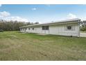 White ranch style home with a metal roof and a well-manicured green lawn, ideal for country living at 2040 Underwood Ln, Zephyrhills, FL 33540