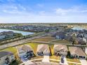 Aerial view of a community showcasing houses, streets, landscaping, and a nearby pond at 2839 Gumbo Limbo Dr, Wimauma, FL 33598