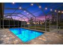 Sparkling pool with screened enclosure, featuring string lights and a scenic view of the outdoors at 4564 Juniper Dr, Palm Harbor, FL 34685