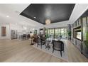 Spacious living room with black accent ceiling, wood-look tile flooring, and large sliding glass doors at 7934 Lakes Edge Ln, Port Charlotte, FL 33981