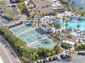 Aerial view of community pool with tennis courts, palm trees, and plenty of seating for residents at 988 Villeroy Greens Dr, Sun City Center, FL 33573