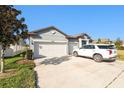This single-story home has a spacious driveway, an attached garage, and a neutral exterior paint scheme at 12593 Palapa Loop, Spring Hill, FL 34610
