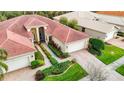 Aerial view of a home with a red tile roof, lush landscaping, and a paver driveway at 16112 Amethyst Key Dr, Wimauma, FL 33598