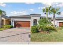 Charming single-story home with well-manicured landscaping, brick driveway, and a beautiful dark wood garage door at 31675 Cannon Rush Dr, San Antonio, FL 33576