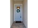 Stylish front door with a wreath, glass pane, 'hello' mat and classic hardware enhancing curb appeal at 31675 Cannon Rush Dr, San Antonio, FL 33576