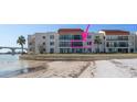 Waterfront condo building with balconies overlooking sandy beach with outdoor seating and waterfront views at 825 S Gulfview Blvd # 208, Clearwater Beach, FL 33767