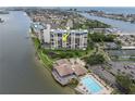Stunning aerial view of waterfront condo showcasing building amenities: pool, dock, and tennis courts at 9425 Blind Pass Rd # 507, St Pete Beach, FL 33706