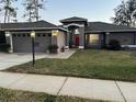 Well-lit home exterior with a two-car garage and a meticulously maintained front lawn at 11138 Brooklawn Dr, Hudson, FL 34667