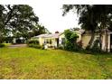 Quaint single-story home featuring a well-maintained lawn and mature trees providing ample shade at 1372 Palmetto St, Clearwater, FL 33755