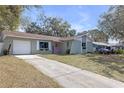 View of single-story home with long driveway leading to attached one-car garage at 245 Faithway Dr, Seffner, FL 33584