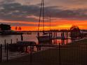 Picturesque sunset view of waterfront with sailboat, palm trees, and a colorful sky reflected in the water at 11145 4Th E St, Treasure Island, FL 33706