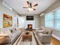 Cozy living room featuring a decorative fireplace, ceiling fan, neutral furniture and large windows at 1276 Sedeeva N Cir, Clearwater, FL 33755