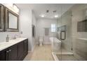 Modern bathroom featuring a double vanity, standalone tub, walk-in shower with glass door, and tiled floors at 1904 Pepperwood Pl, Brandon, FL 33510